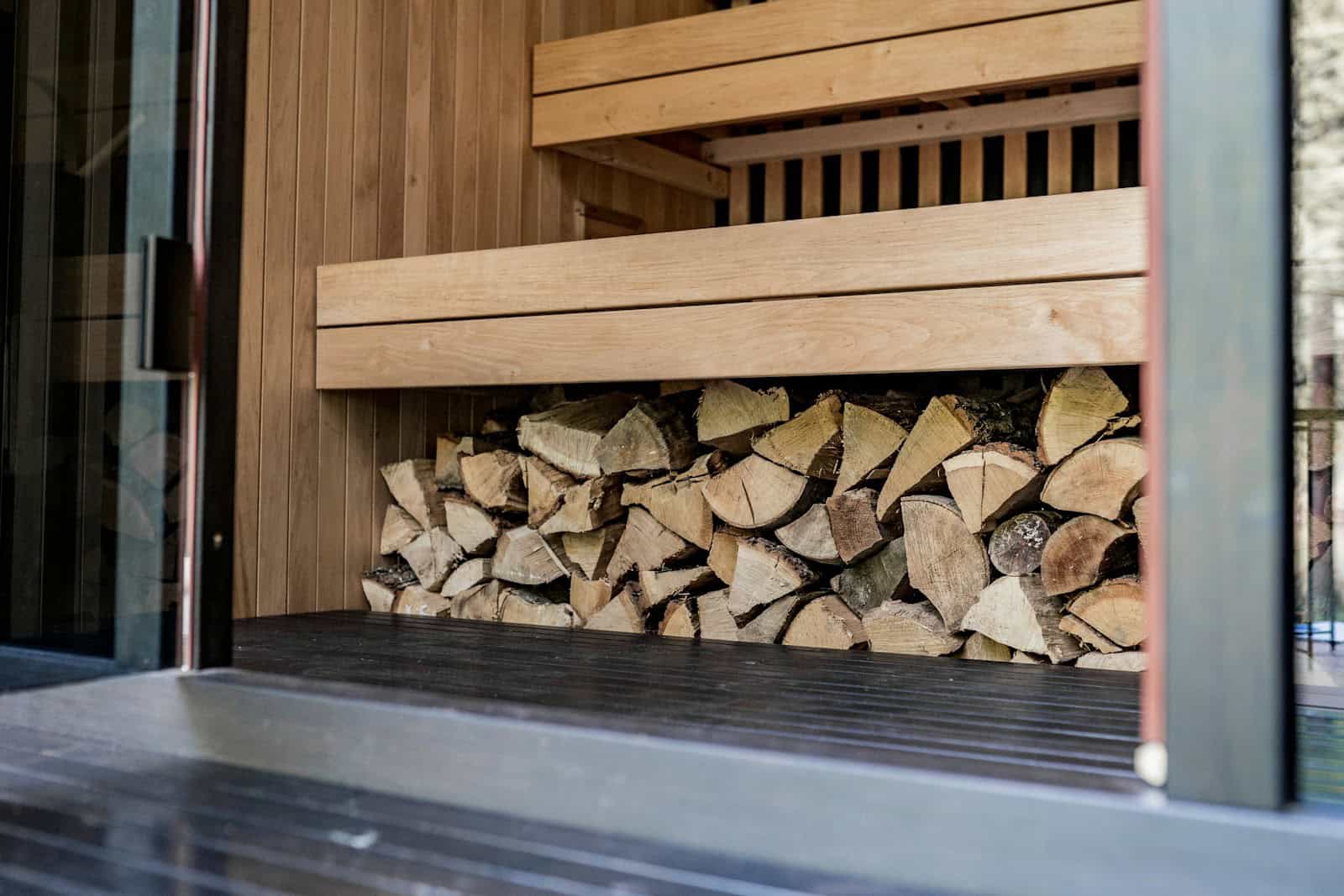 Holzbank in einer Kräutersauna mit frischen Kräuterbündeln auf den Saunasteinen